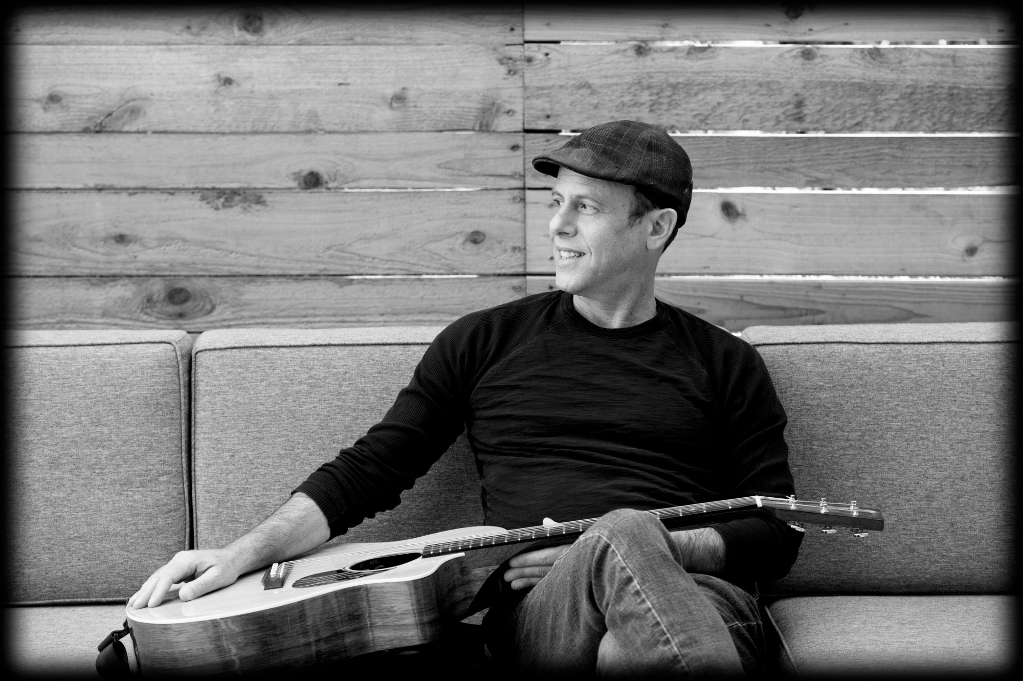 Peter Gross relaxed on couch with guitar
